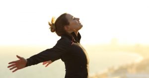 Woman breathing breathing in fresh air with arms outstretched